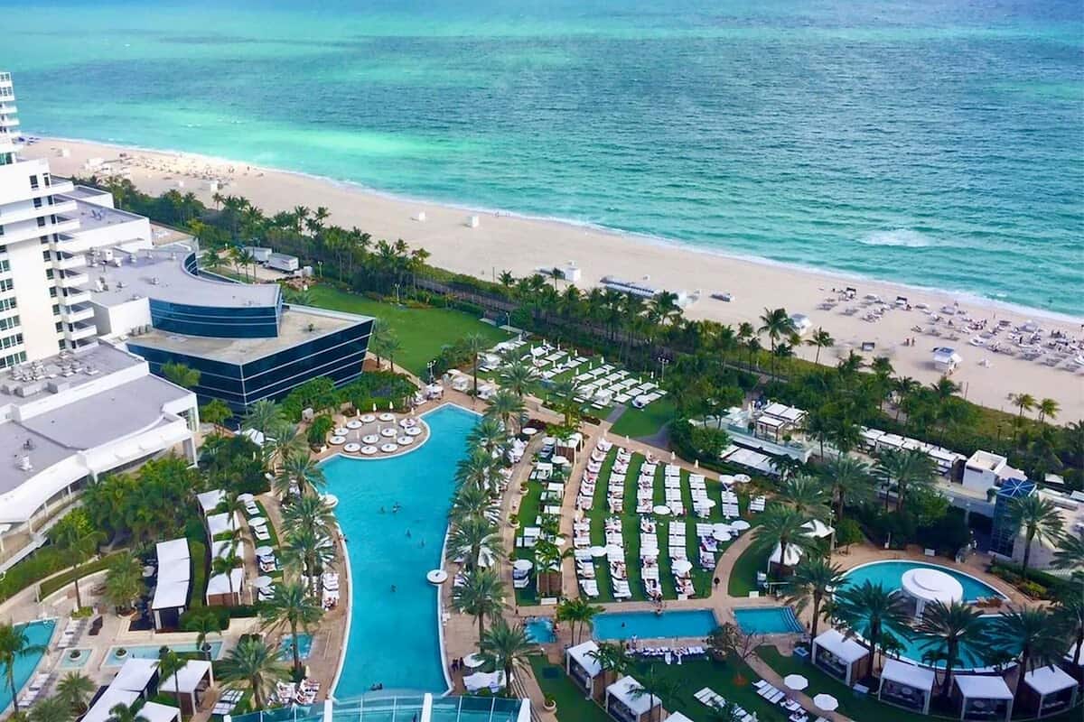 Een resort met een centraal gelegen zwembad, diverse loungegedeeltes en een strand.