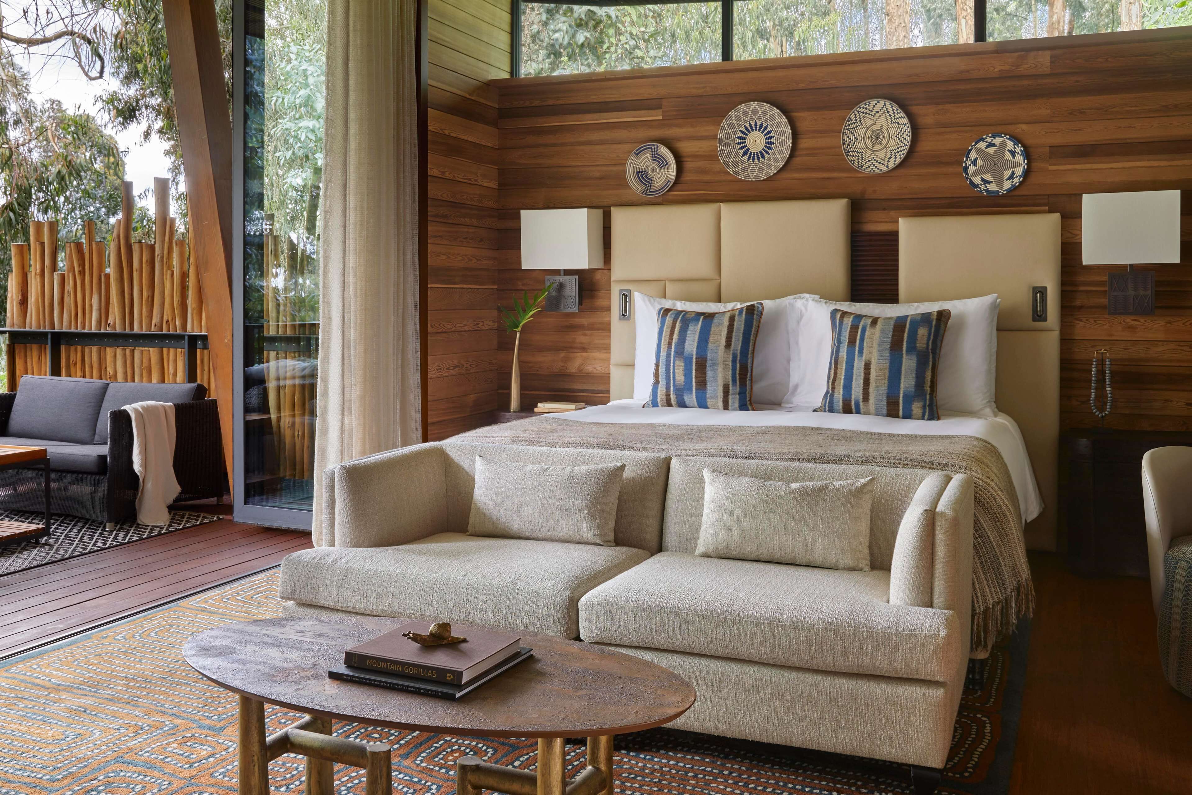 A bedroom with a large bed, a sofa, a coffee table, and a wooden wall with decorative plates.