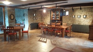 A dining area with a stone wall, wooden furniture, and a fireplace.