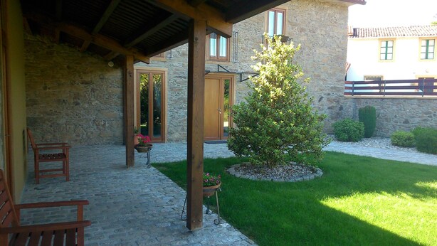 A stone building with a covered patio area, a small tree, and a chair.