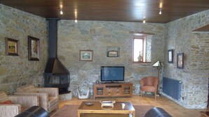 A stone-walled living room with a fireplace, a television, and a sofa.