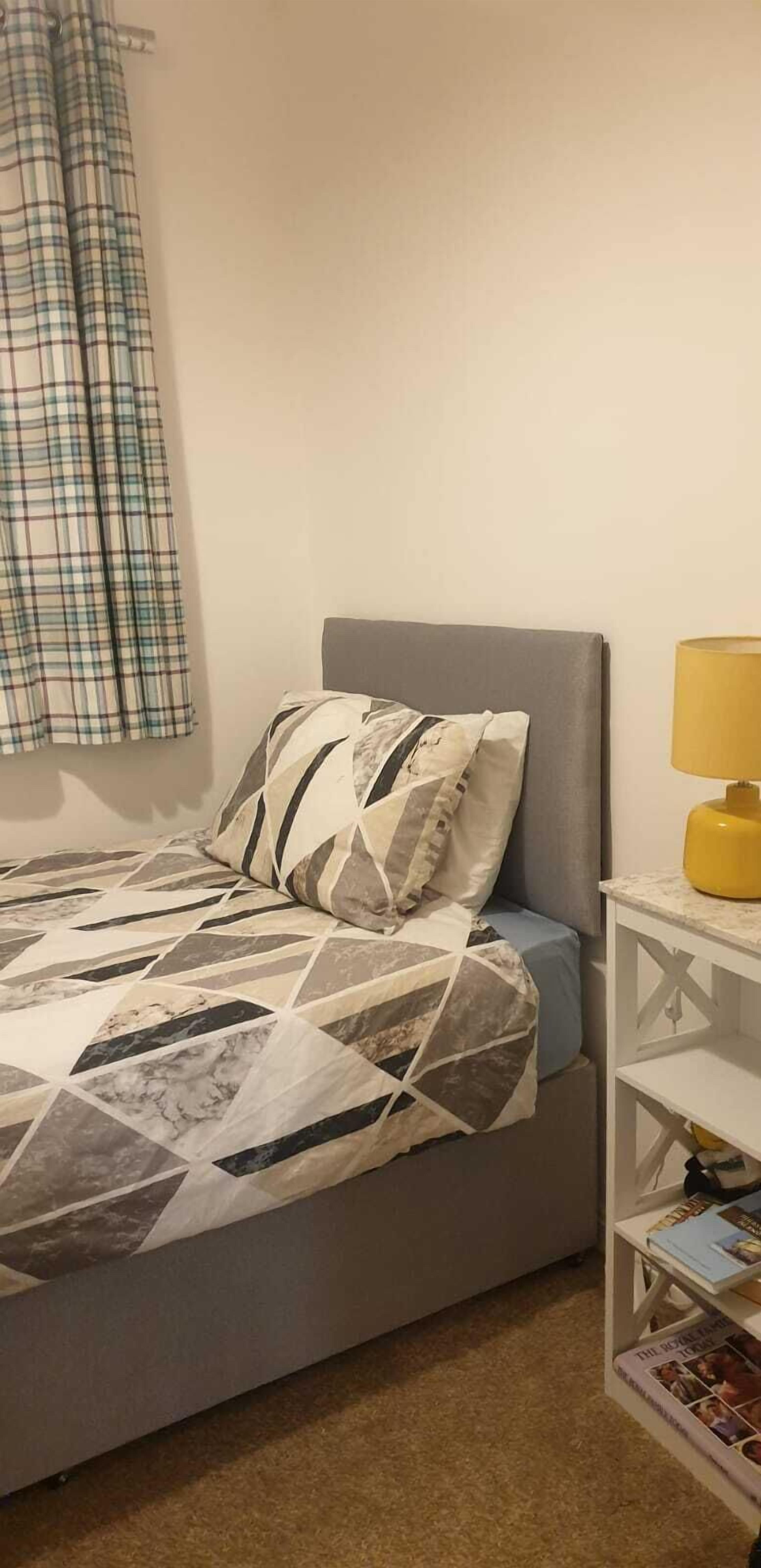 Une chambre à coucher avec un lit, un oreiller, une lampe et une étagère remplie de livres.