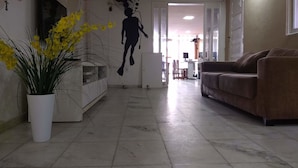 Una sala de estar con un sofá, una planta en maceta y una pared decorada con un diseño en silueta.