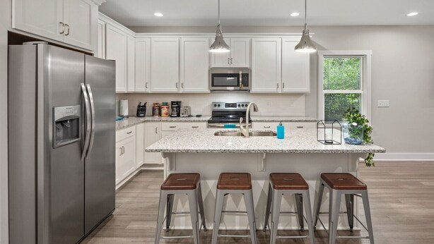 A modern kitchen with white cabinets, stainless steel appliances, granite countertops, and bar stools. - Luxurious 8 bd/6ba with ROOFTOP! Price is the total! (Nashville)