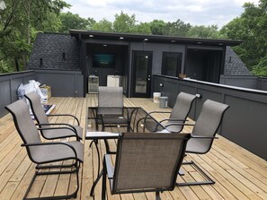 An outdoor deck with four chairs and a table, a kitchen area, and a large screen. - Luxurious 8 bd/6ba with ROOFTOP! Price is the total! (Nashville)