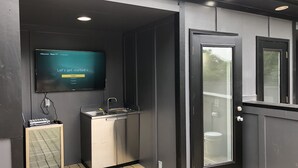 A compact, modern outdoor kitchen area with a built-in sink and a television mounted on the wall displaying a language selection screen. - Luxurious 8 bd/6ba with ROOFTOP! Price is the total! (Nashville)