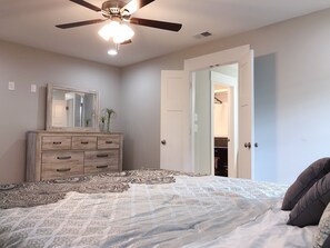 A bedroom with a bed, a dresser, a ceiling fan, and an open closet door. - Luxurious 8 bd/6ba with ROOFTOP! Price is the total! (Nashville)