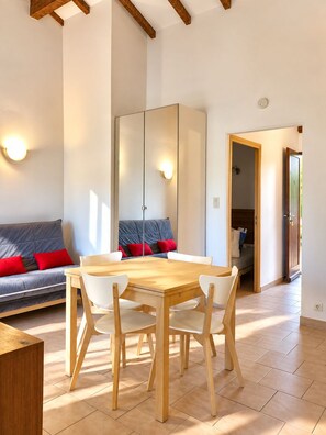 A modern living room with a sofa, a dining table with chairs, and a wardrobe.