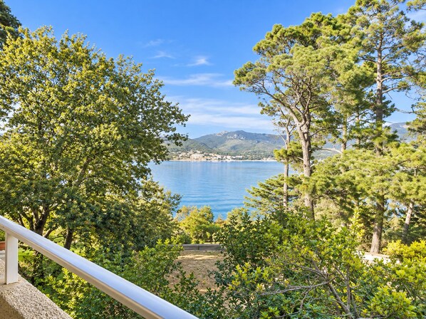 A coastal landscape with a clear view of the sea and distant hills.