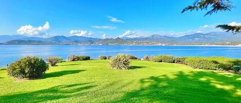 A well-maintained grassy area with a view of a large body of water and distant mountains.