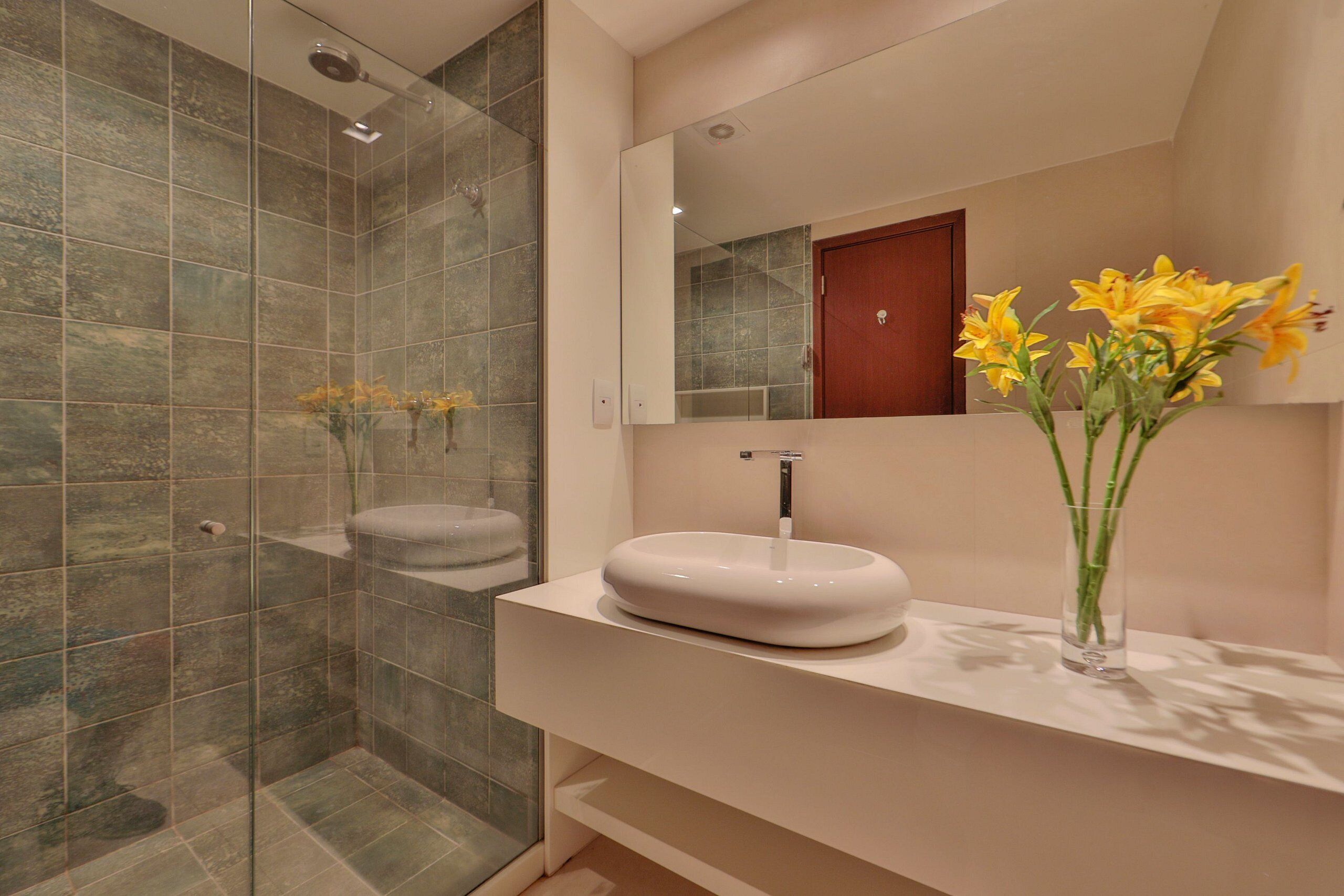 A bathroom with a glass shower enclosure, a white sink, and a mirror above it.