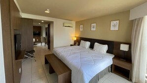 A hotel room with a bed, bedside tables, a TV, a bench, and a desk. - HY Beach Flats - International (Recife)