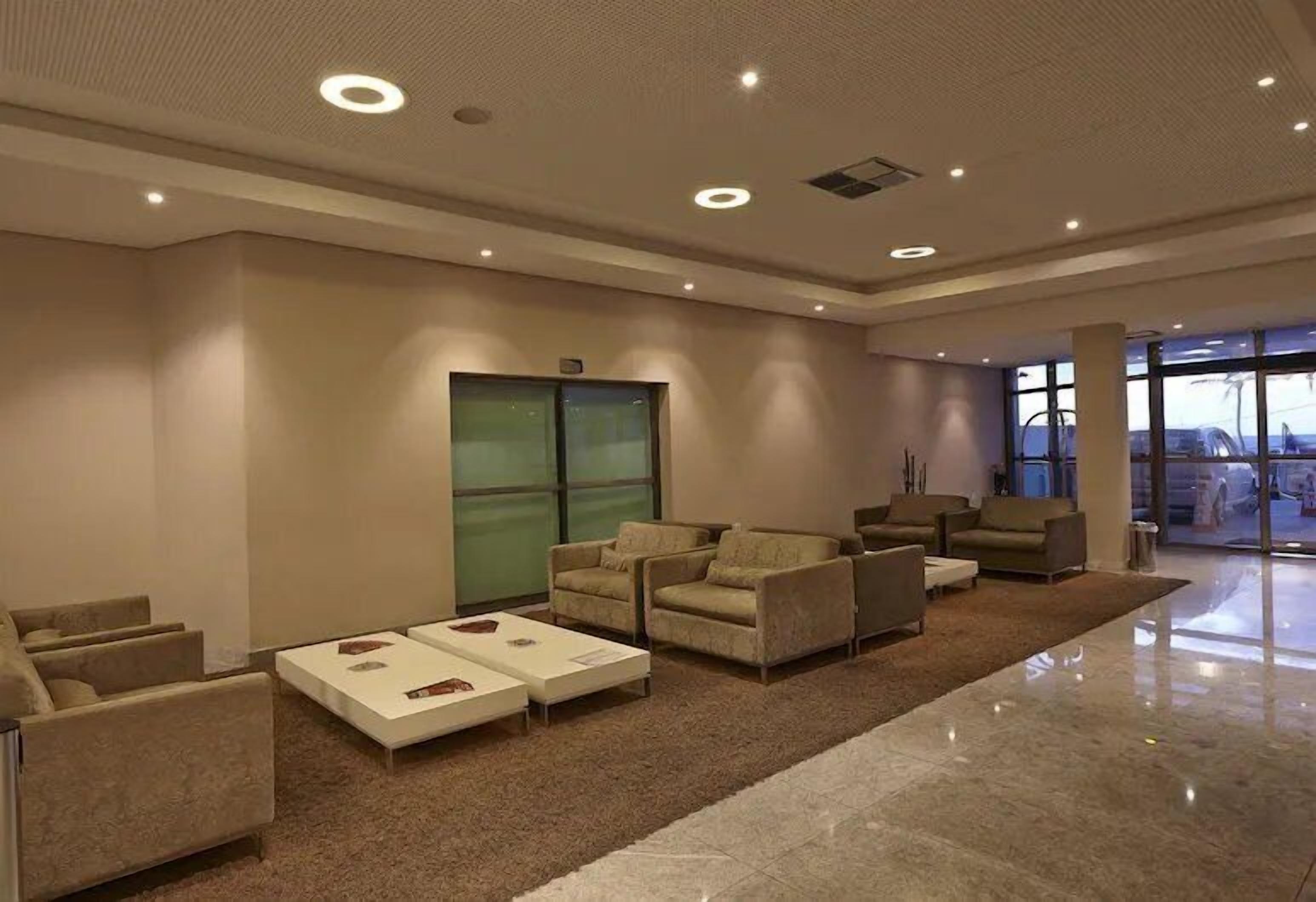 A spacious lobby with sofas, a coffee table, and a glass elevator.