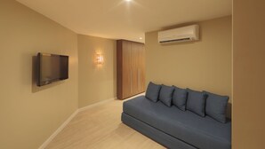 A modern living room with a flat-screen TV mounted on the wall, a sofa with cushions, and an air conditioning unit. - HY Beach Flats - International (Recife)
