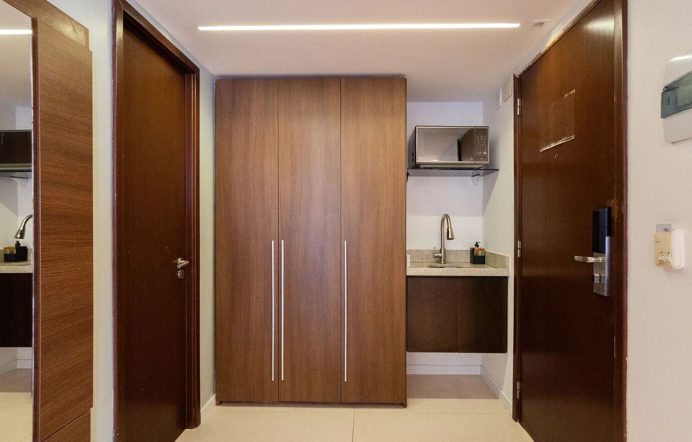 A modern kitchen with wooden cabinets, a microwave, and a sink.