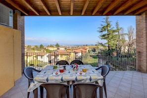 A patio with a table set for two, overlooking a residential area with houses and trees. - Pegaso (Polpenazze del Garda)