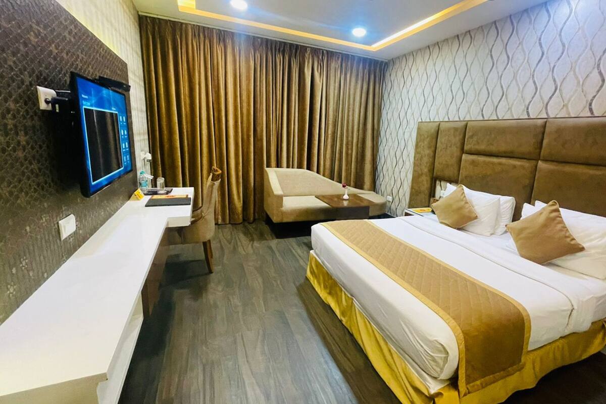 A hotel room with a bed, a desk, a chair, and a TV.