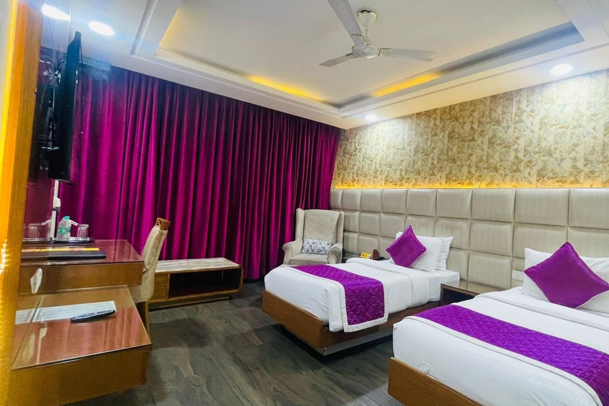 A hotel room with two beds, a desk, a chair, and a television.