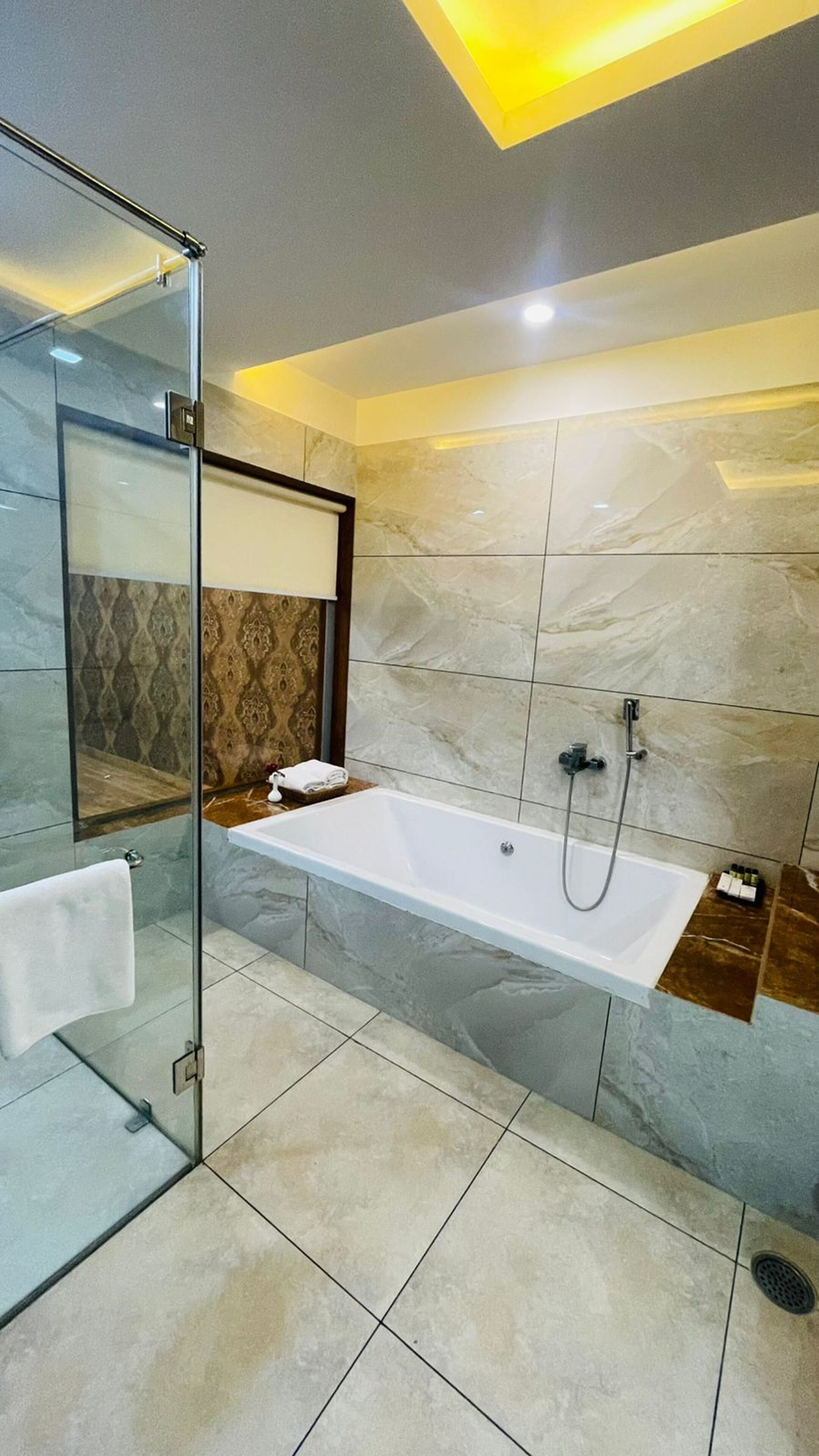 Un baño moderno con cabina de ducha de vidrio, una bañera independiente y paredes de mármol.