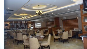 Um restaurante espaçoso com várias áreas de refeição, luminárias modernas e um design limpo e contemporâneo.