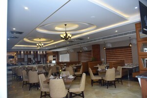 Un restaurante espacioso con varias zonas de comedor, modernos accesorios de iluminación y un diseño limpio y contemporáneo.