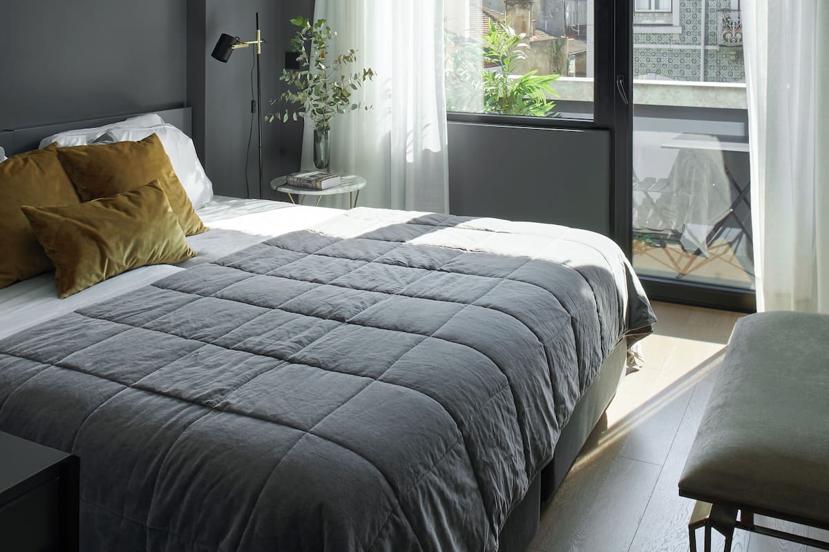 Un dormitorio moderno con una cama grande, una mesita de noche, una silla y vistas al balcón.