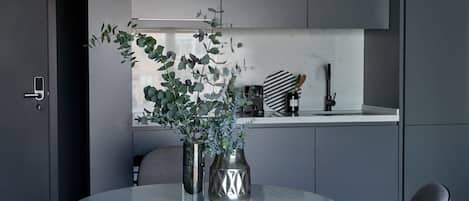 Un comedor moderno con una mesa redonda, dos sillas, un florero con plantas y una lámpara original.