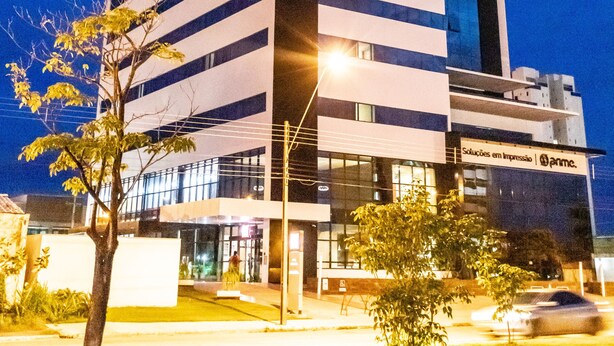 Un moderno edificio de hotel con un llamativo letrero que dice “Ibis Hotel”, que presenta una fachada limpia con líneas verticales y una estructura alta con una pantalla digital en la parte superior.