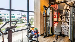 Un gimnasio con equipo de ejercicio, una cinta de correr y vistas al exterior.