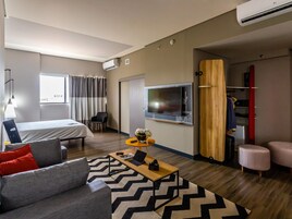 A modern hotel room with a bed, a sofa, a coffee table, a TV, and a wardrobe.