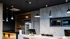 Un área de bar moderna con mostrador, taburetes y un refrigerador lleno de bebidas.