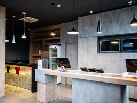 A modern bar area with a counter, bar stools, and a refrigerator stocked with beverages.