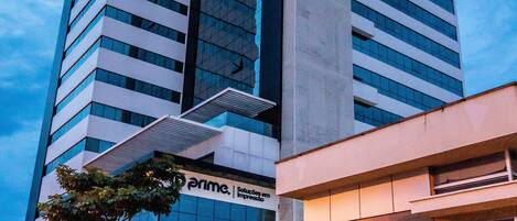 A modern high-rise hotel with a prominent "Ibis Hotel" sign, featuring a sleek glass facade and a vertical design.