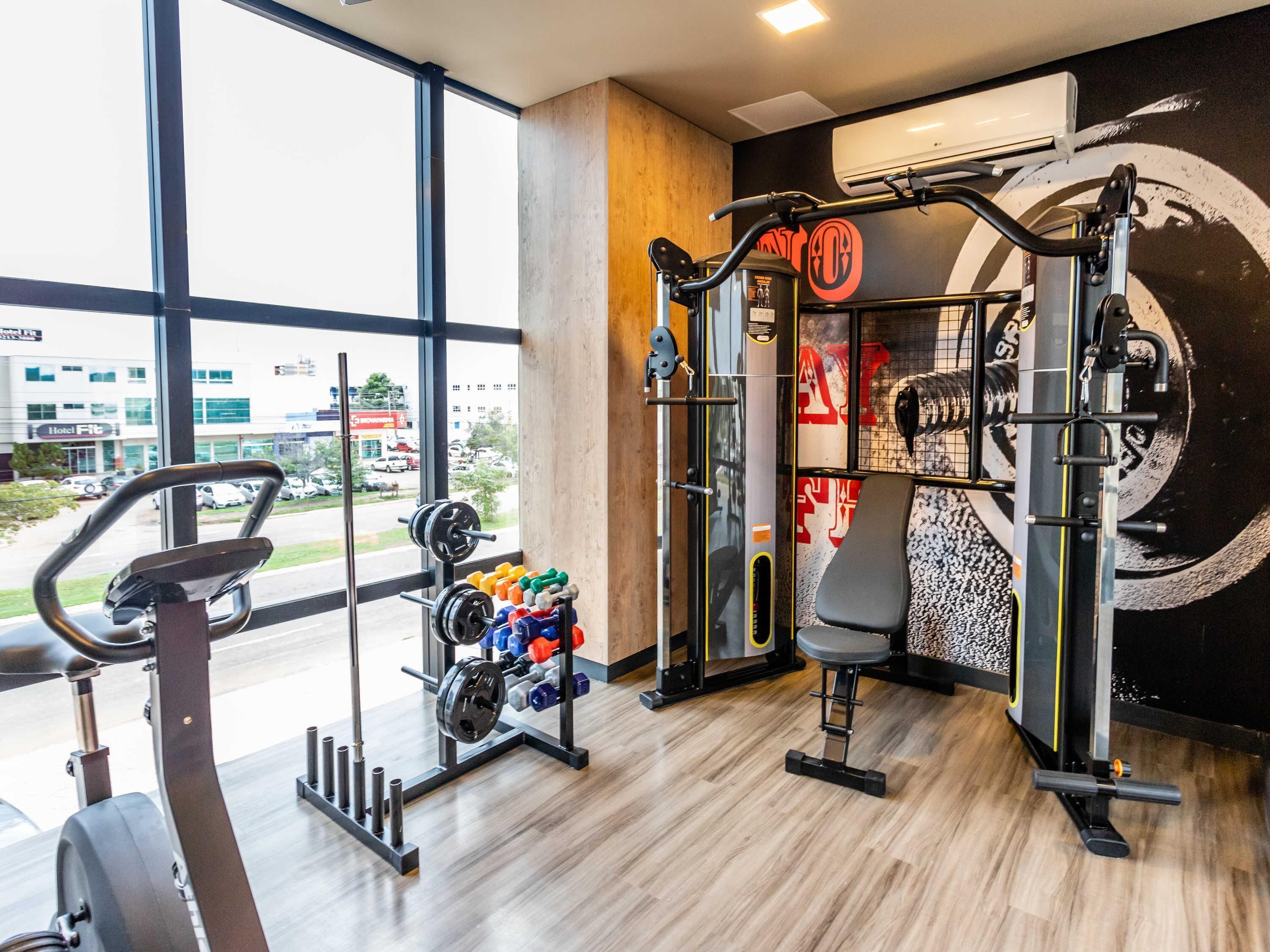 Un gimnasio con diversos equipos, incluyendo una cinta de correr, jaulas para pesas y un rack para sentadillas.
