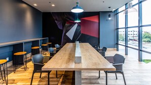 Un salón de conferencias moderno con una mesa larga, sillas y un gran ventanal que ofrece vistas al exterior.