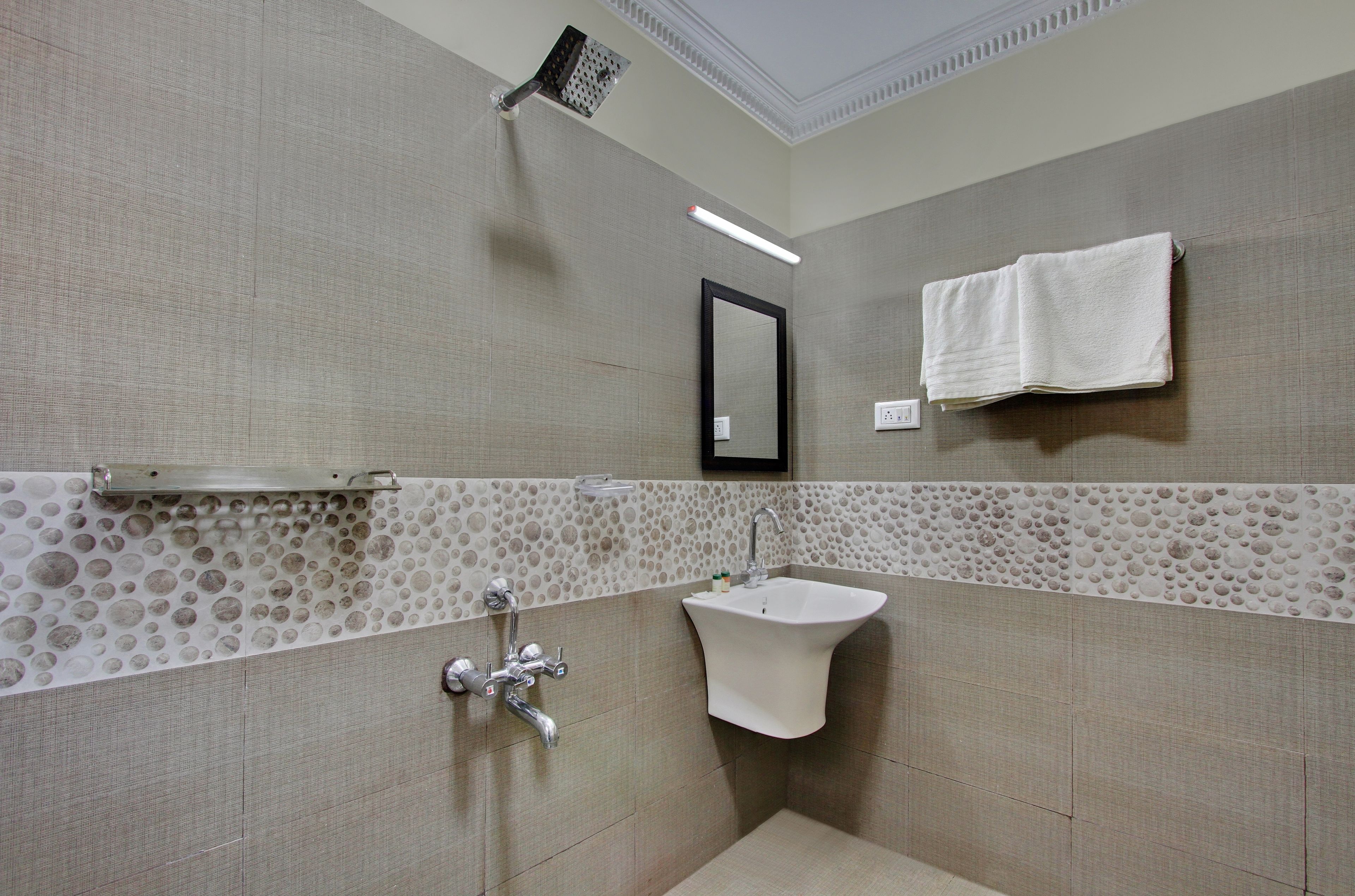 A bathroom with a sink, mirror, towel rack, and shower.