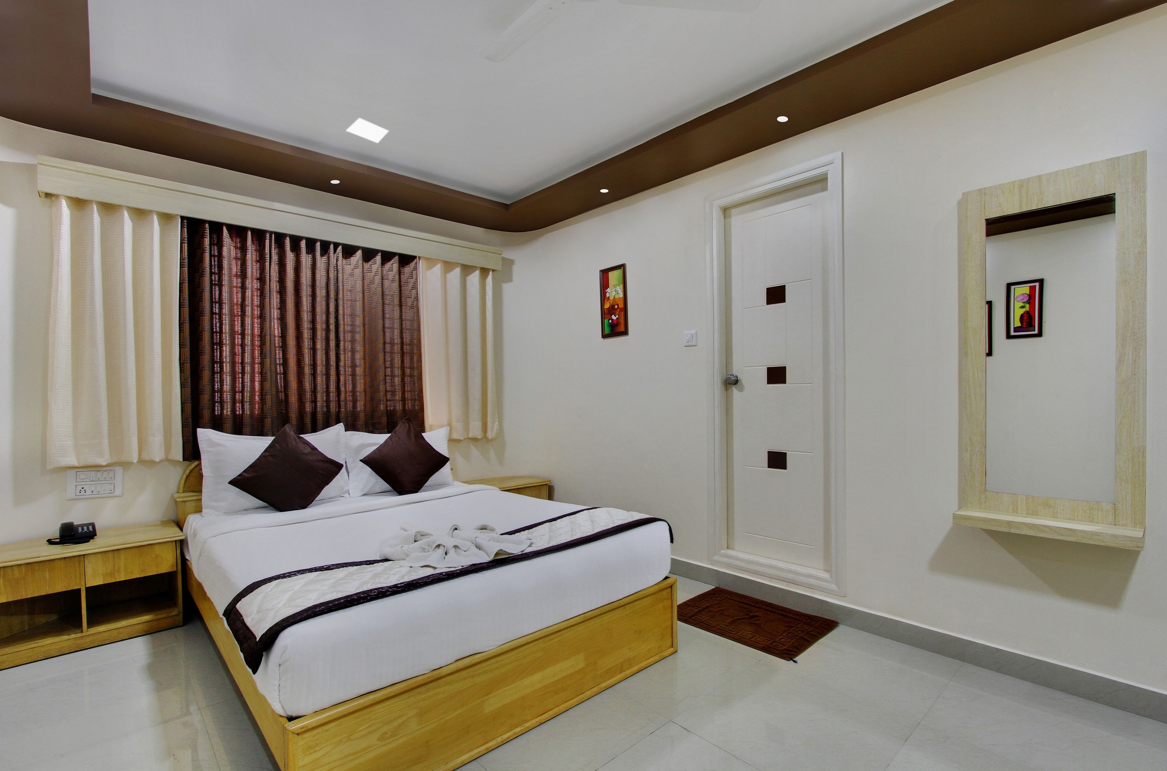 A neatly arranged bedroom with a bed, bedside tables, a wardrobe, and a mirror.