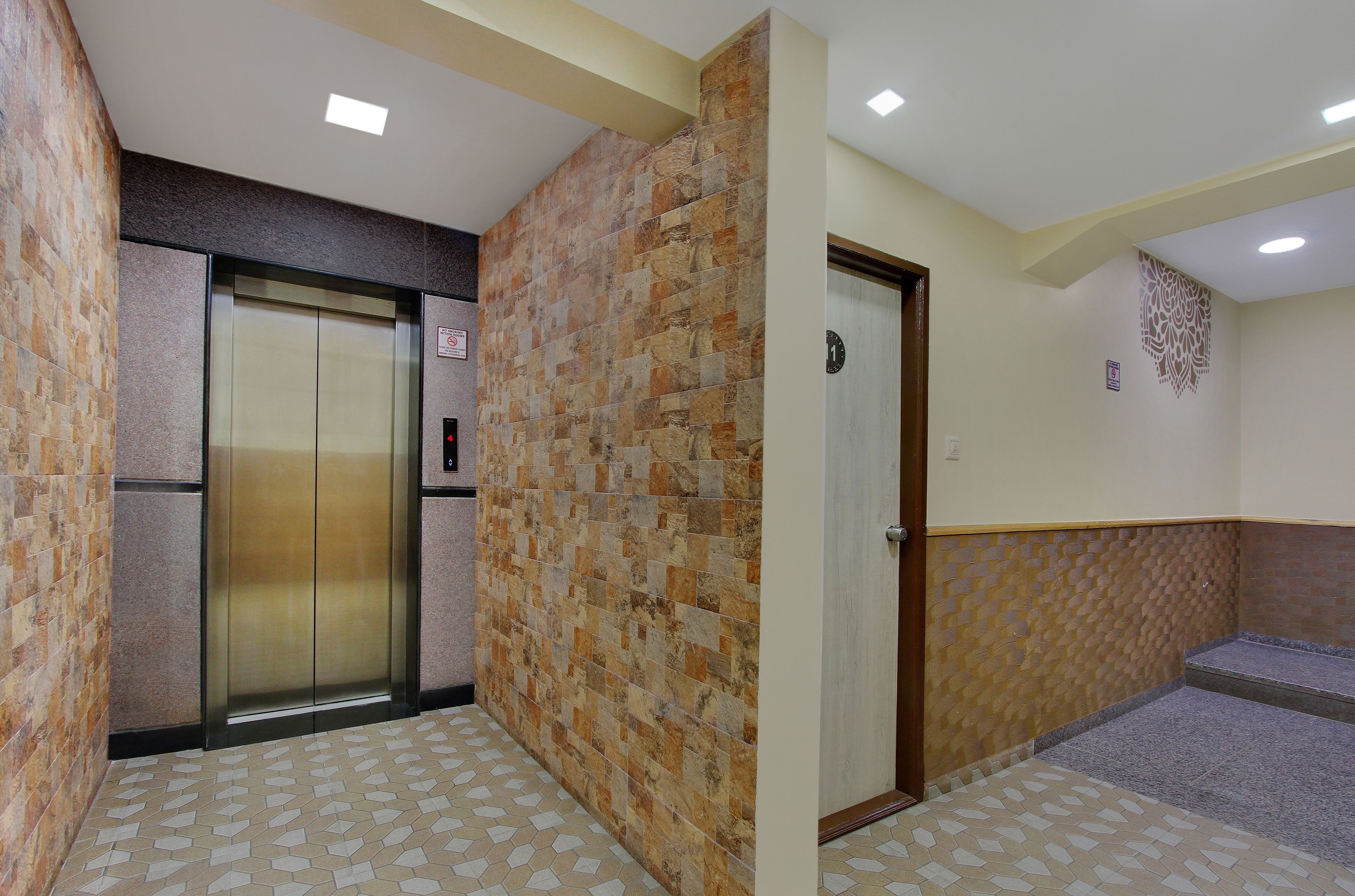 An elevator in a hallway with patterned walls and a tiled floor.
