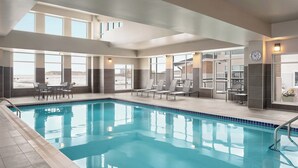 A swimming pool with clear blue water, surrounded by lounge chairs and a sun terrace with large windows. - Residence Inn by Marriott Des Moines Ankeny (Ankeny)