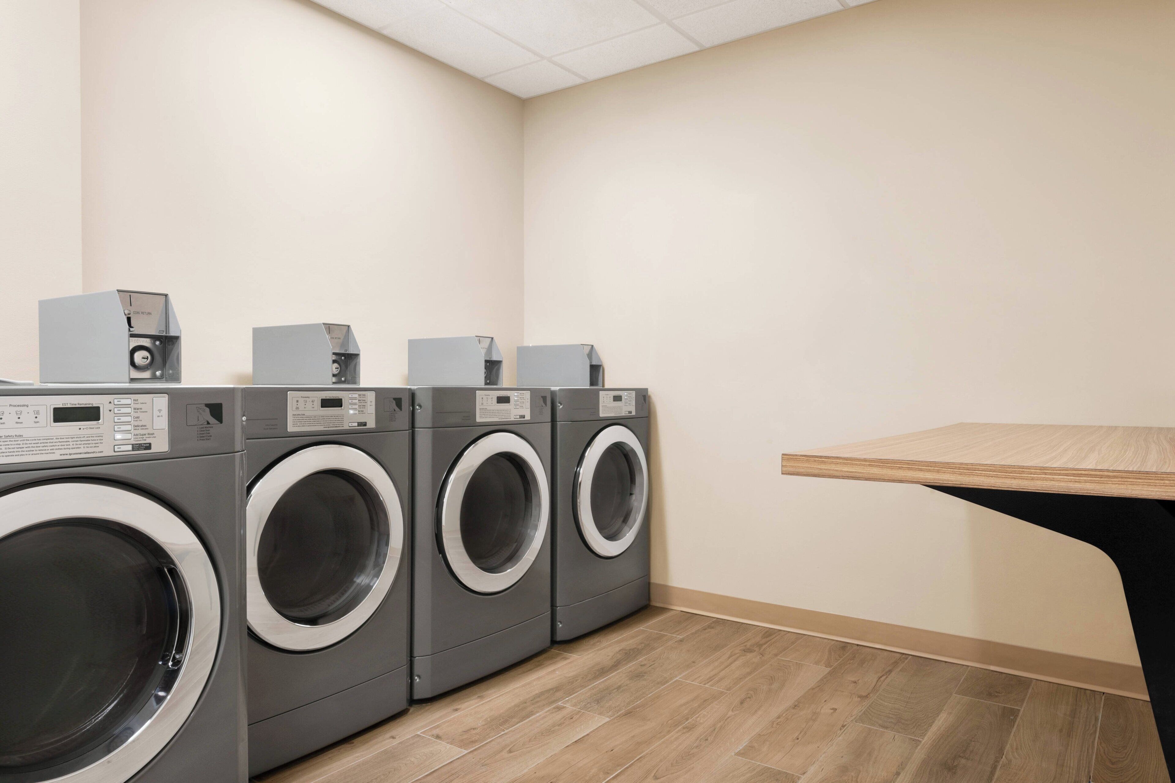 A laundry room with three front-loading washing machines and a table.