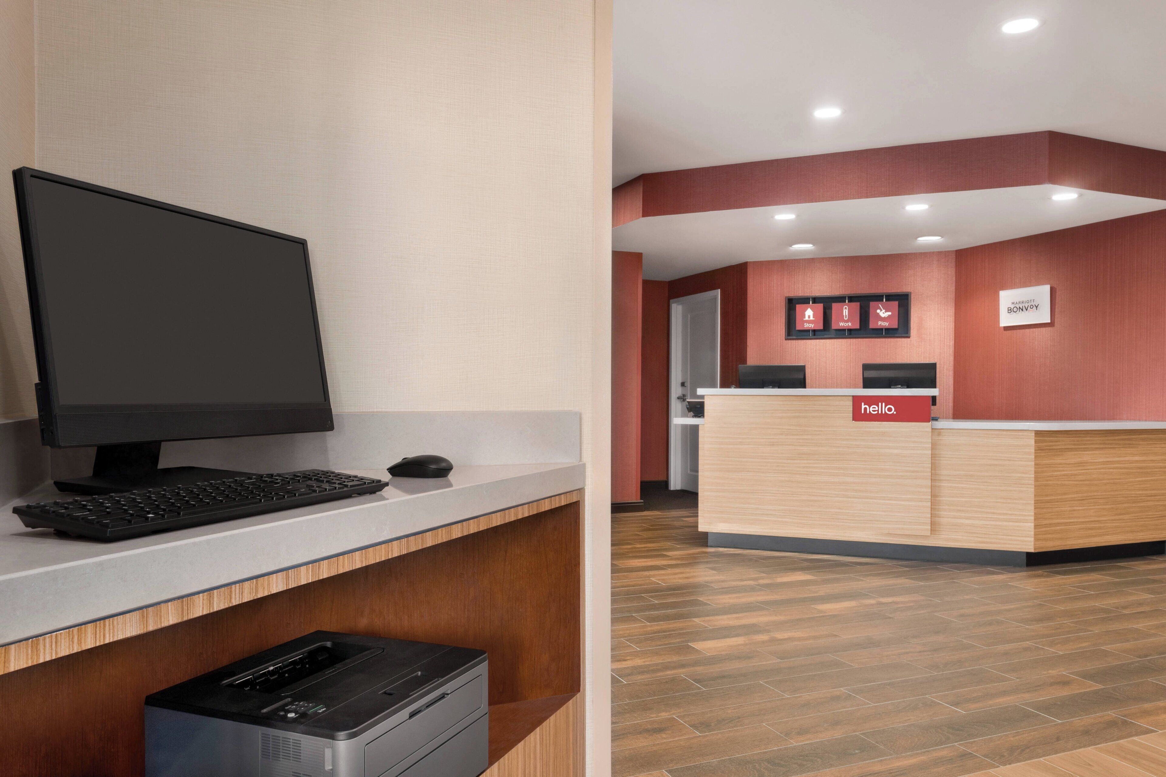 A reception desk with a "hello" sign, a computer setup, and a wooden counter.