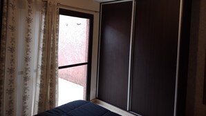 A room with a large window, a wardrobe, and a bed.