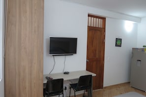 Cozy retreat with a flat-screen TV, compact dining area, and a convenient refrigerator.