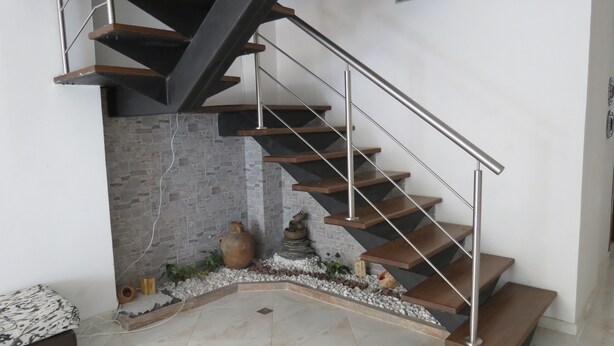 A modern staircase with a metal railing, wooden steps, and a stone wall. - Apartamentos MED (Medellín)