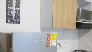 A compact kitchen with a refrigerator, microwave, and sink. - Apartamentos MED (Medellín)