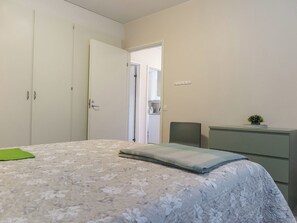 Une chambre à coucher avec un lit, une armoire, un bureau et une petite plante.