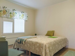 Un dormitorio con cama, dos ventanas con persianas, un escritorio y una silla.