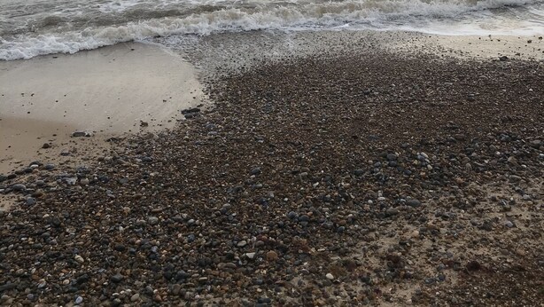 En strand med småsten och vågor.