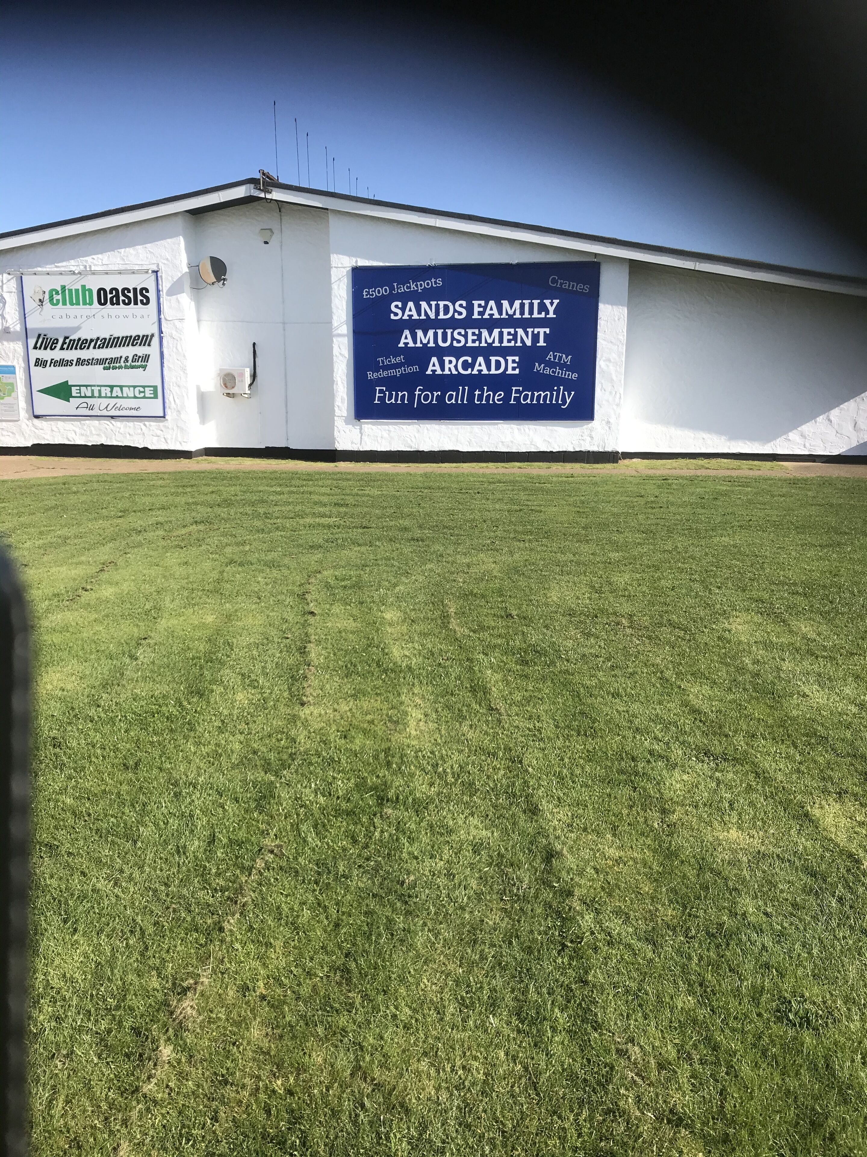 A building with a sign for Club Oasis and Sands Family Amusement Arcade.