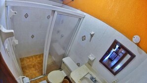 Un baño pequeño con inodoro, lavamanos y cabina de ducha.